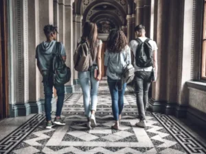Group of diverse college students walking in a university building.