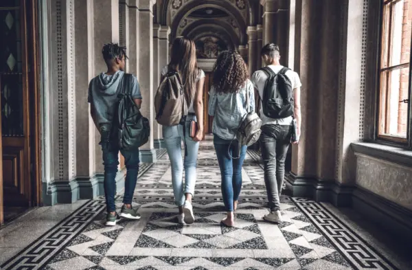 Group of diverse college students walking in a university building.